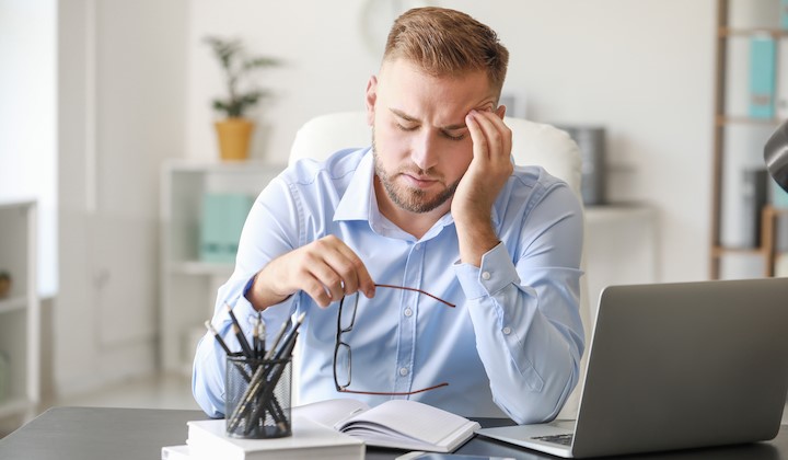 Mann mit stressigem Alltag Gestresster Mann am Schreibtisch